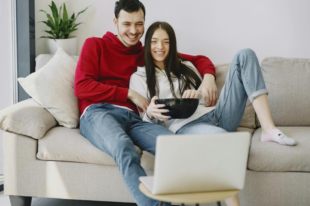 happy couple watching movie on laptop in apartment